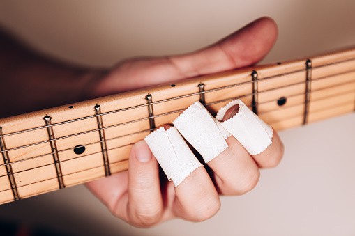 Sore fingers with bandage playing guitar